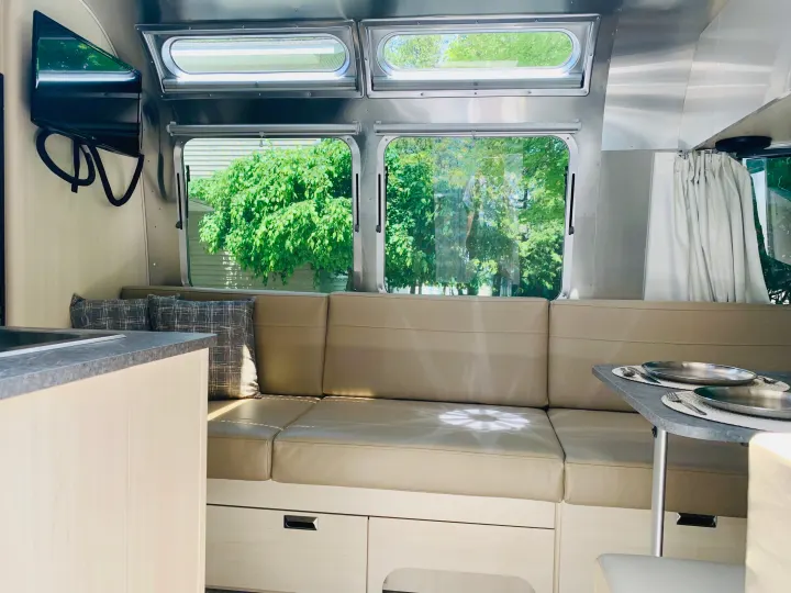 Comfortable RV rental interior featuring a spacious lounge, dining area, and large windows with outdoor views.. Airstream Flying Cloud 2022