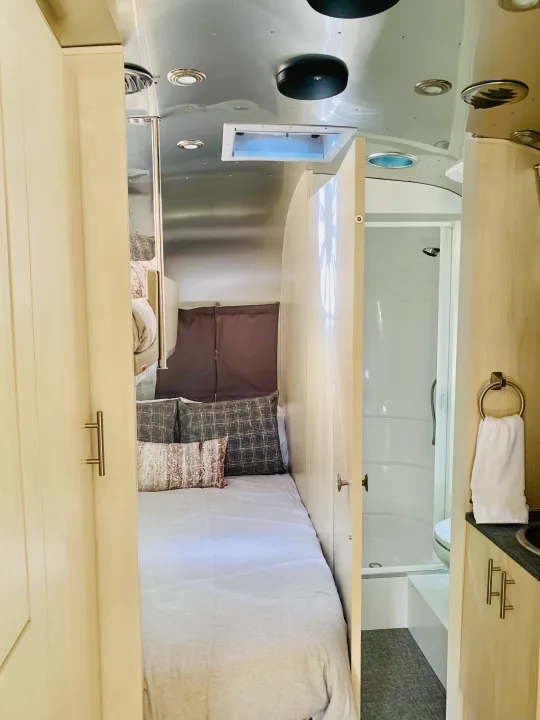 Cozy RV rental interior: bed, shower, and sink vanity setup for comfortable mobile living.. Airstream Flying Cloud 2022