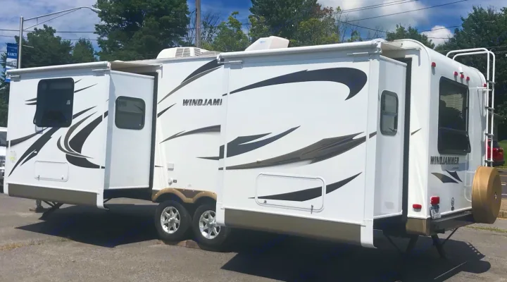 Large white Windjammer travel trailer RV rental with slide-outs extended, parked on asphalt.. Forest River Rockwood Windjammer 2012