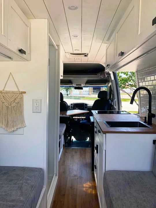 Modern rv rental interior with kitchen, seating, and overhead cabinets. Ideal for comfortable van life.. Mercedes-Benz Sprinter 2015