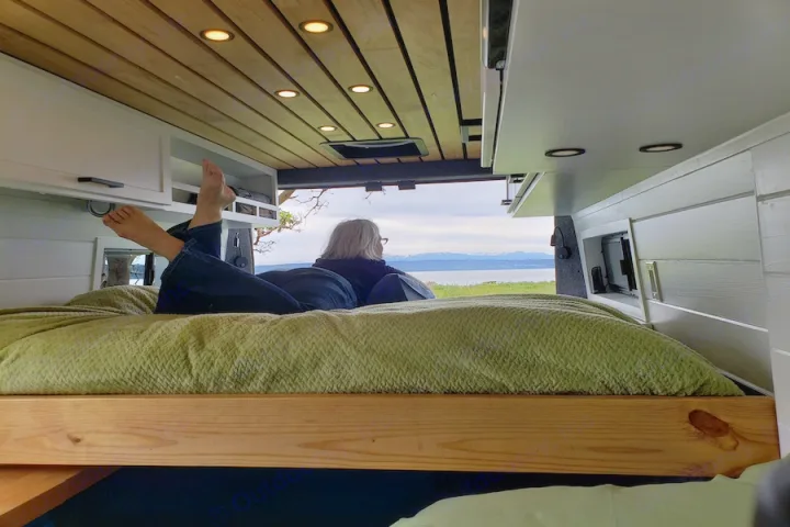 Enjoying the view from an RV rental's cozy bed. This camper van offers comfort with a stunning lake and mountain vista.. Dodge Promaster 2500 2021