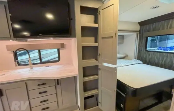 RV rental interior featuring a modern kitchenette, mounted TV, ample storage, and a cozy bedroom.. Forest River Solera 2022