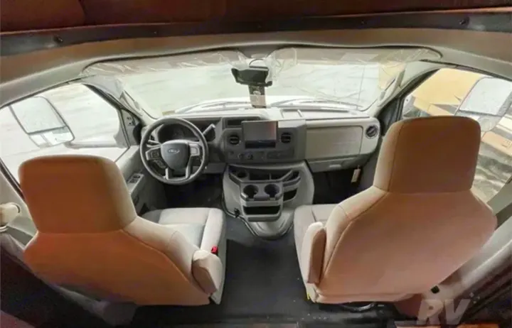 Front interior of an rv rental: Driver and passenger seats face a clean Ford dashboard and steering wheel.. Forest River Solera 2022
