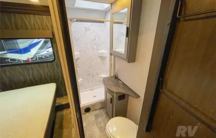 Inside an RV rental: View of a functional bathroom with shower, toilet, and sink, alongside a comfortable bedroom area.. Forest River Solera 2022