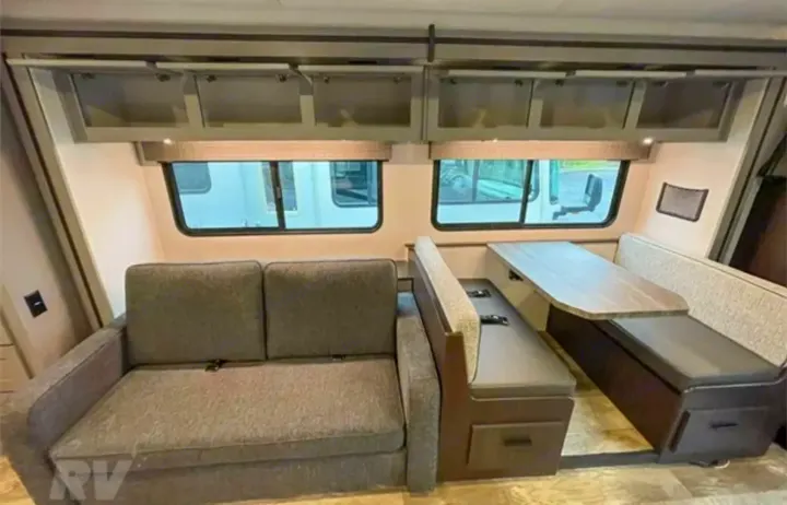 RV rental interior: a comfy grey sofa, a dinette with table & benches, and overhead cabinets provide a functional living space.. Forest River Solera 2022