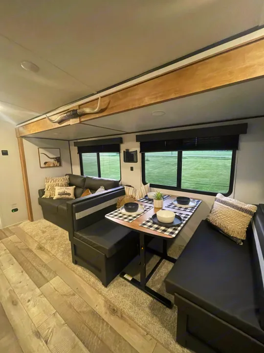 Cozy RV rental interior featuring a modern dining booth, sofa, and longhorn decor above.. Keystone Springdale 2022