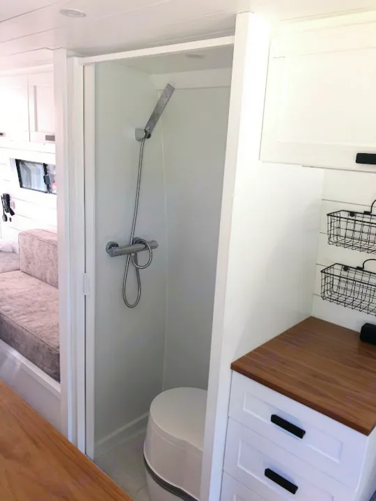 Compact RV rental bathroom: shower, composting toilet, and stylish white cabinetry. Bright, modern interior.. Mercedes-Benz Sprinter 2015