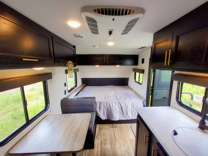 Inside an RV rental: cozy bed, dinette, and kitchen counter with sink. Ready for your camping or road trip adventure.. Forest River Cherokee Wolf Pup 2022