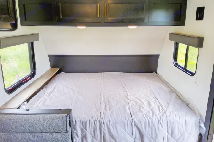 Cozy RV rental bedroom featuring a large bed, storage cabinets, and side windows with natural light.. Forest River Cherokee Wolf Pup 2022