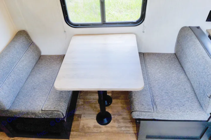 Cozy RV rental dinette with light table, facing benches, and window views. Ideal for a travel trailer.. Forest River Cherokee Wolf Pup 2022