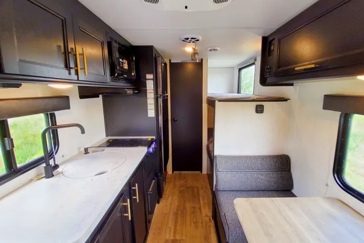 RV rental interior: modern kitchen, dinette with table, and bunk beds. Functional, compact travel space.. Forest River Cherokee Wolf Pup 2022