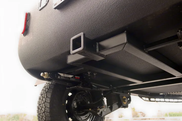 Underside view of an RV rental's robust rear hitch receiver, stabilizer jack, and suspension for reliable adventure travel.. Oregon Trail'R DoDrop ALPHA 2021