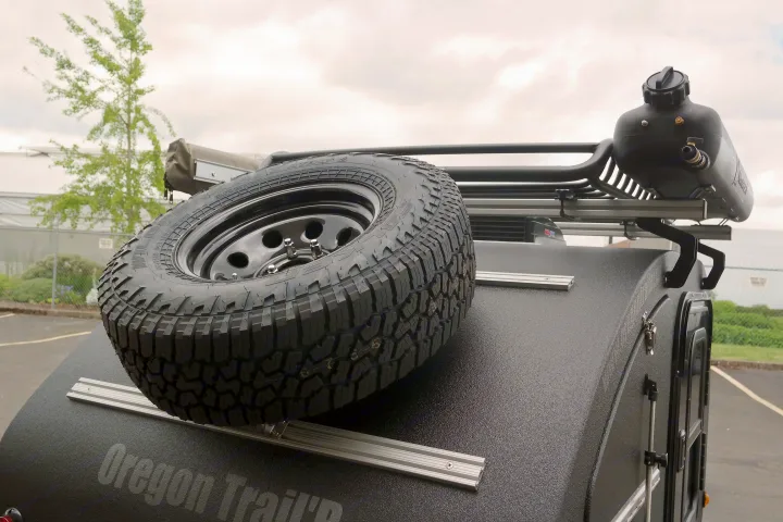 Off-road RV rental trailer featuring a mounted spare tire, roof rack, and water tank. Ready for adventure.. Oregon Trail'R DoDrop ALPHA 2021