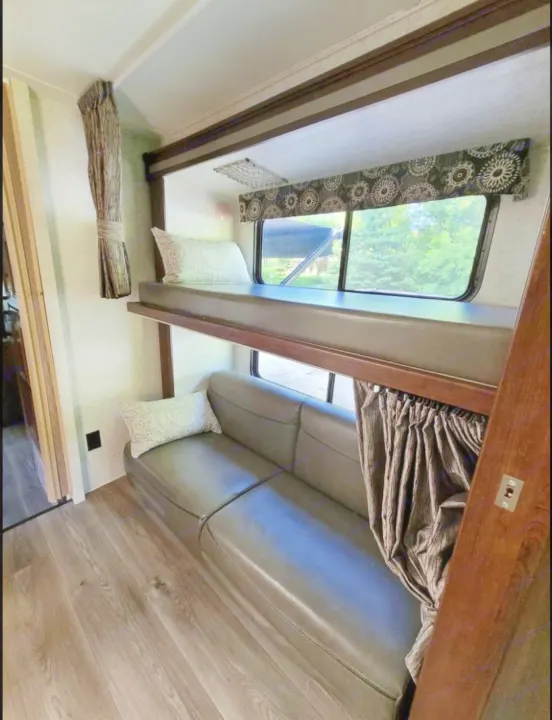 RV rental interior showing bunk beds, a sofa, and wood flooring. A cozy, functional living space for travel.. Forest River Sunseeker 2017