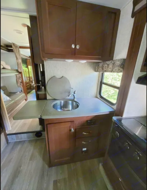 Explore this RV rental's cozy interior, complete with kitchen, sink, upper cabinets, bunk beds, and lounge area.. Forest River Sunseeker 2017