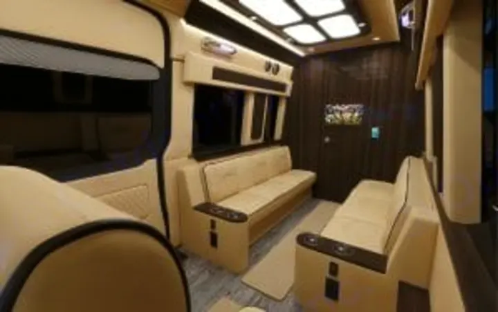 Luxury RV rental interior: Plush cream seating, wood walls, and a TV define this custom van's high-end mobile lounge.. Ultimate Toys Ultimate Traveler 2023