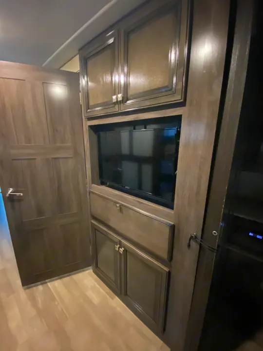 RV rental interior featuring a built-in entertainment system with a TV, dark wood cabinets, and ample storage.. Flair-Fleetwood Flair-Fleetwood Motorhome 2020