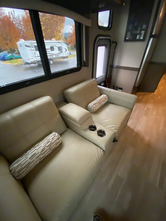 RV rental: Cozy living area with light recliners, cup holders, pillows, and windows showing an outside RV.. Flair-Fleetwood Flair-Fleetwood Motorhome 2020