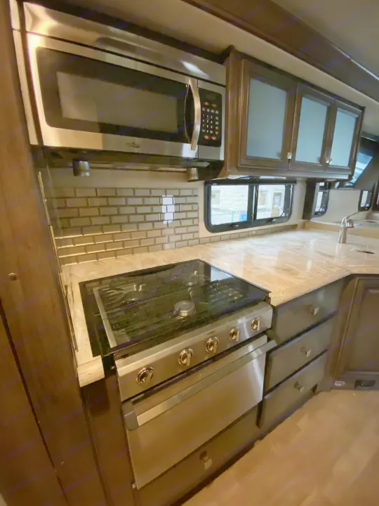 RV rental: Modern Dometic kitchen with built-in microwave, oven, sleek cabinets, and tiled backsplash for travel.. Flair-Fleetwood Flair-Fleetwood Motorhome 2020