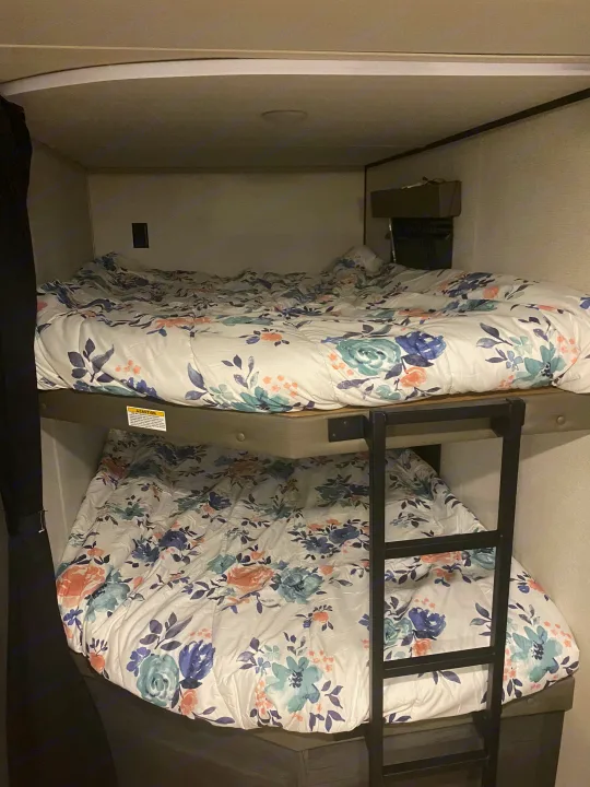 RV rental sleeping area: Twin bunk beds with matching floral comforters, offering cozy lodging.. Keystone Hideout 2022