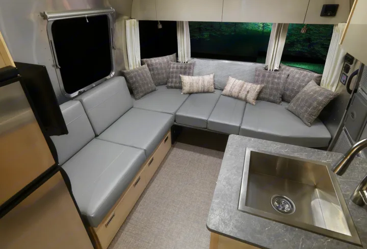Spacious RV rental interior with convertible gray sofa, sink, and fridge. Perfect for road trips!. Airstream Flying Cloud 25RB 2022