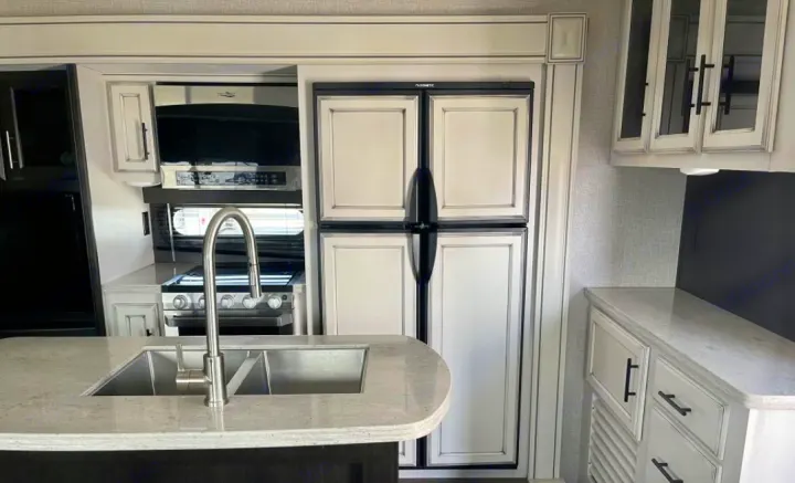 Explore this modern RV rental kitchen: light countertops, large sink, Dometic refrigerator, microwave, and stove.. Jayco Eagle HT 2020