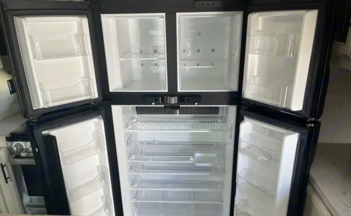 Inside this RV rental, a multi-door refrigerator and freezer stands empty & open, ready for adventure provisions.. Jayco Eagle HT 2020