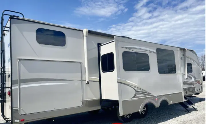 This modern beige RV rental is a travel trailer with an extended slide-out, tinted windows, and a rear access ladder.. Jayco Eagle HT 2020