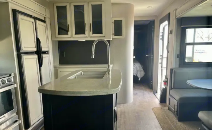 Spacious RV rental interior featuring a modern kitchen island, refrigerator, dining booth, and bedroom access.. Jayco Eagle HT 2020