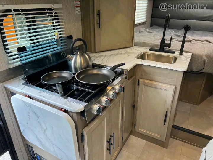 Modern RV rental interior: Kitchen with stove, sink, and bed for comfortable travel.. Forest River Coachmen Cross Trail XL 2022