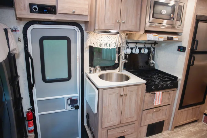 RV rental interior: A compact kitchen area featuring a sink, stovetop, microwave, and refrigerator, designed for efficient travel.. Forest River Forester MBS 2018