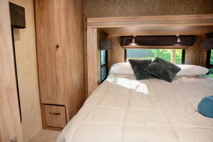 Cozy RV rental bedroom with a comfy bed, bright windows, and wood storage cabinets.. Forest River Forester MBS 2018