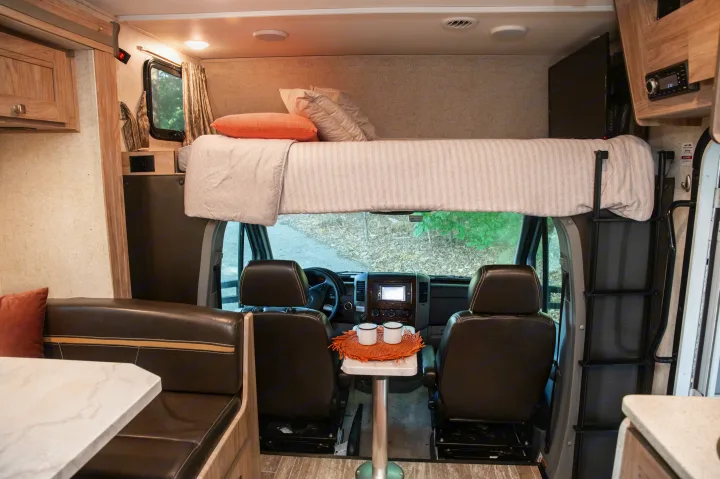 Spacious RV rental interior featuring an over-cab bunk bed, dinette, kitchen, and dashboard area.. Forest River Forester MBS 2018