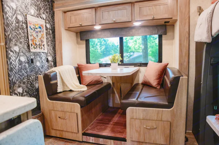 Cozy RV rental dinette with dark benches, light table, and window view, perfect for travel dining.. Forest River Forester MBS 2018