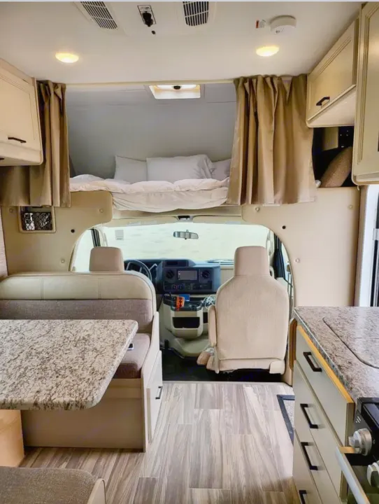 Inside this modern **rv rental**: a comfy overhead bed, dining nook, kitchen, and cockpit. Ready for adventure.. Thor Freedom Elite 2022