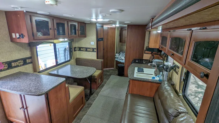 Explore this comfortable rv rental interior featuring a dinette, kitchen with stove and sink, and lounge, ideal for a camper's adventure.. Heartland RVs North Trail 2013