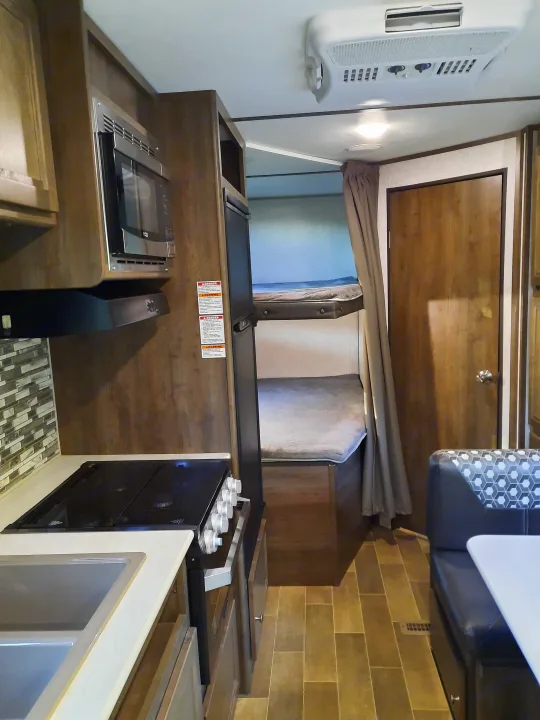 RV rental: Interior view of compact living space featuring kitchen with microwave, stove, dinette, and wall-mounted AC.. Dutchmen Coleman Lantern LT 2020