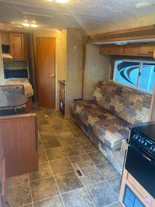 Inviting RV rental interior: patterned sofa, kitchen, bunks, dining nook, wood cabinets, and tiled flooring.. Forest River Salem 2011