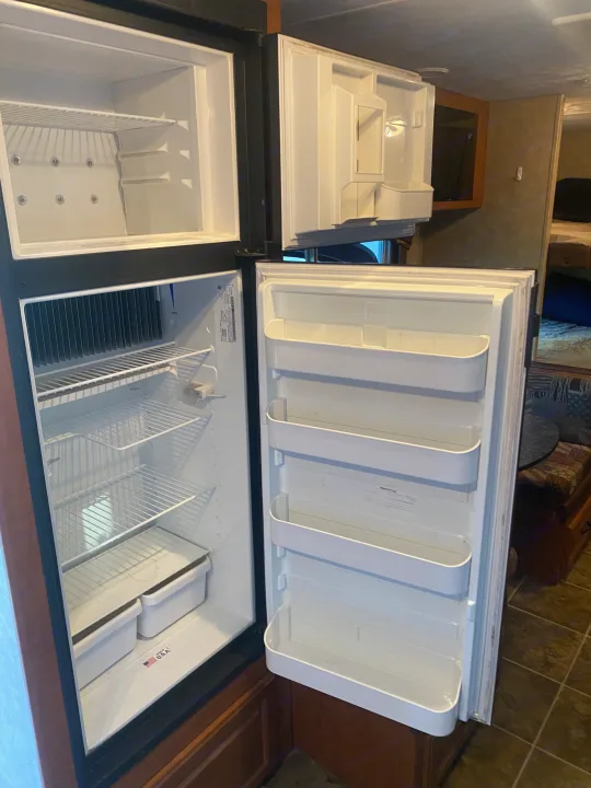 Empty, open RV refrigerator and top freezer, showcasing shelves and door bins, ideal for an rv rental.. Forest River Salem 2011