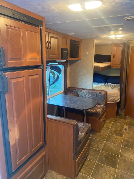 Step inside this RV rental, showcasing a comfortable dinette, kitchen with fridge, and cozy bunk beds.. Forest River Salem 2011