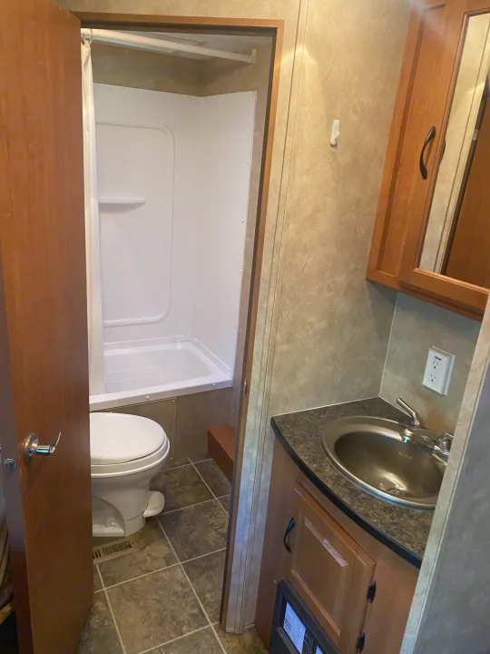 Compact RV rental bathroom featuring a toilet, bathtub/shower, and sink vanity.. Forest River Salem 2011