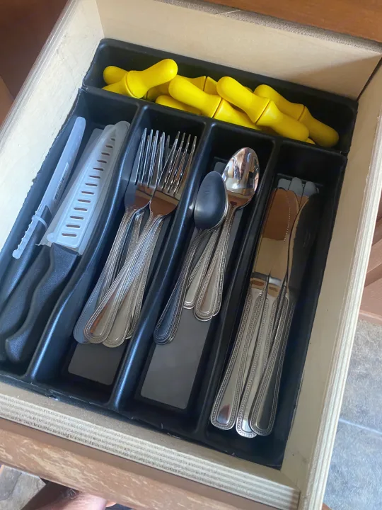 RV rental kitchen drawer: a utensil organizer holds knives, forks, spoons, and many small yellow items.. Forest River Salem 2011