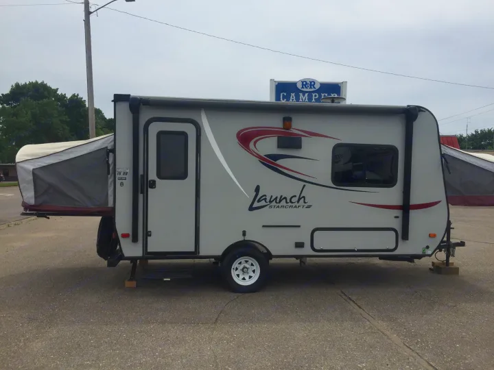 Grey Starcraft Launch hybrid RV rental, a compact travel trailer with pop-out beds, parked on asphalt.. Starcraft Launch 2016