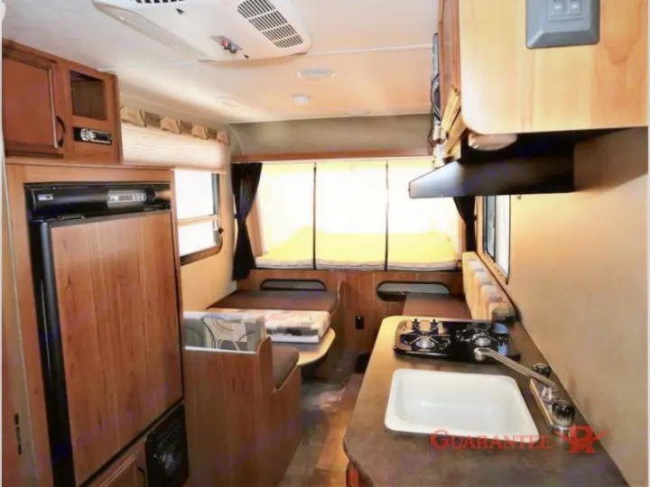 Spacious RV rental interior featuring a functional kitchenette (sink, stove, fridge), dinette, and pop-out bed space.. Starcraft Launch 2016