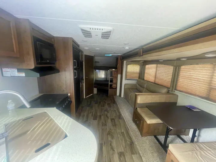Spacious RV rental interior with kitchen (sink, stove, microwave), dinette, sofa, and bunks.. Keystone Cougar Half-Ton 2018