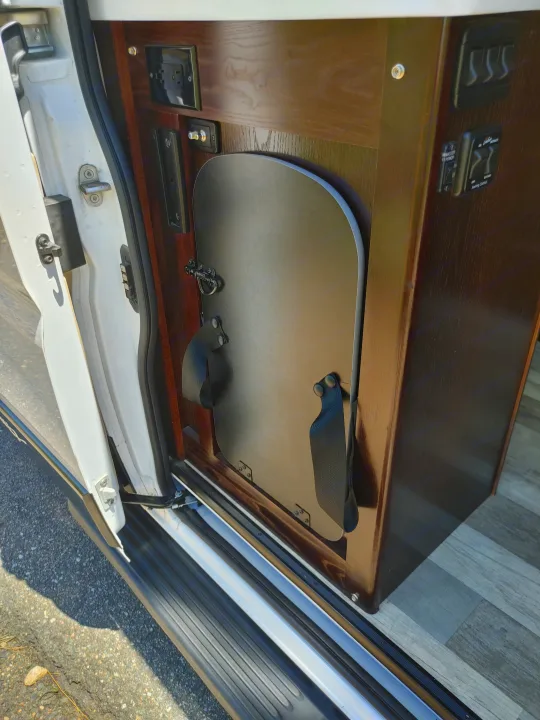 RV rental interior: sliding door with power outlets, control panel, and a versatile folding table for optimal space use.. Regency RV National Traveler 2019