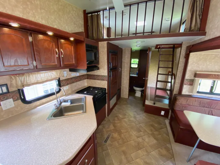 Spacious RV rental interior featuring a full kitchen, dining area, and upper loft bunk. Perfect for family travel.. Other Other 2009