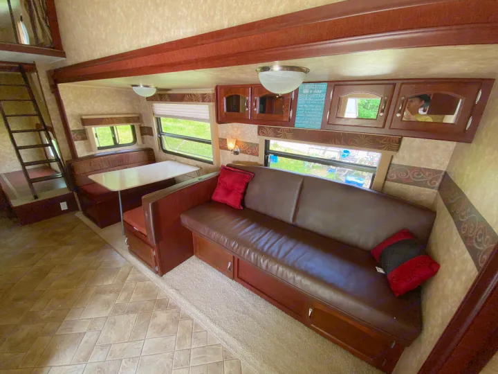 Spacious RV rental interior featuring a cozy dinette, leather sofa, overhead cabinets, and loft access. Perfect for your next adventure.. Other Other 2009