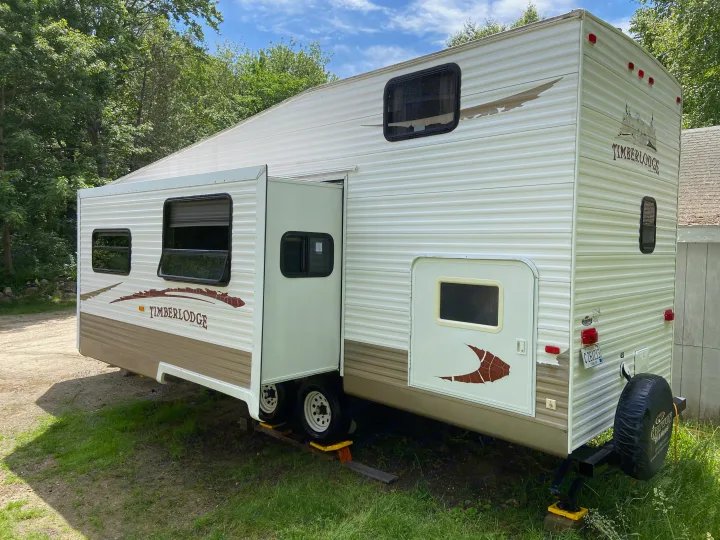 White Timberlodge travel trailer with a slide-out, available for RV rental. Parked in a natural setting.. Other Other 2009