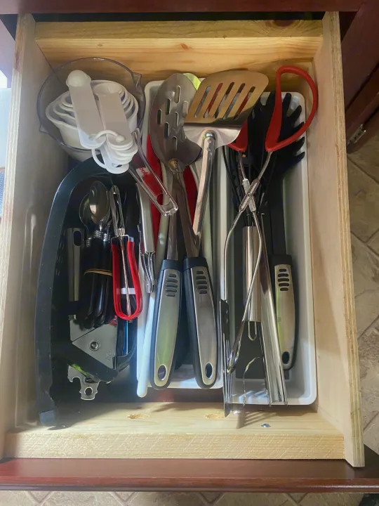 A neatly organized kitchen drawer in an RV rental, filled with various cooking utensils including spatulas, tongs, and measuring cups.. Other Other 2009